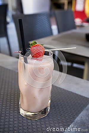 Raw food smoothie with strawberry and blackberry in crystal glass. No people. empty outdoor bar in grey. Waiting for Stock Photo