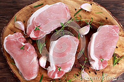 Raw Fresh Boneless Pork Chops with herbs. on wooden board. Stock Photo