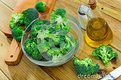 Raw green broccoli pieces in glass bowl, vegetarian food Stock Photo