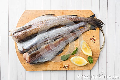 Raw fresh Pollock fish on a wooden Board with lemon Stock Photo