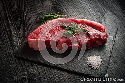 raw fresh strip loin steak on black wooden background Stock Photo