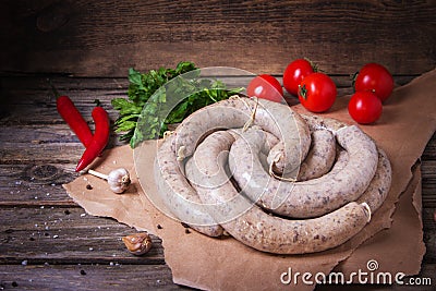 Raw fresh white sausages on a craft paper with vegetables. Weisswurst in a heap. Traditional Bavarian or Munich white sausage made Stock Photo
