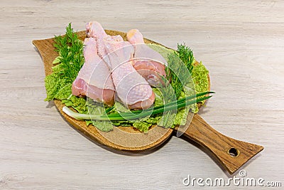 Raw, greasy, chicken thighs on a lettuce leaf. Board for cutting chicken. Stock Photo