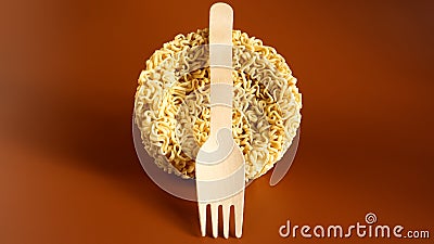 Raw instant noodles in the shape of a circle with a wooden disposable fork. pasta, for the preparation of which it is enough to Stock Photo