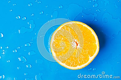 Raw juicy citrus fruit cut in half orange on wet blue background with water drops splashes. Summer beverages refreshments drinks Stock Photo