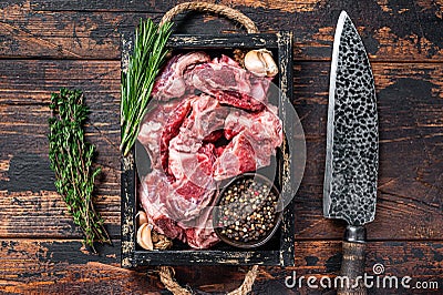 Raw lamb or goat meat diced for stew with bone. Dark wooden background. Top view Stock Photo