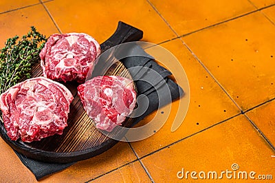 Raw lamb neck chops, fresh mutton meat on a butcher board with herbs. Orange background. Top view. Copy space Stock Photo