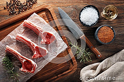 Raw lamb rib chops on white cooking paper and wooden cutting table Stock Photo