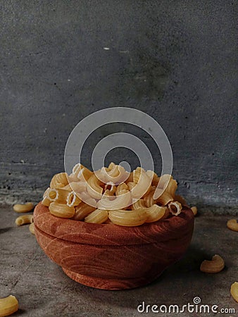 Raw macaroni with wooden bowl on table Stock Photo