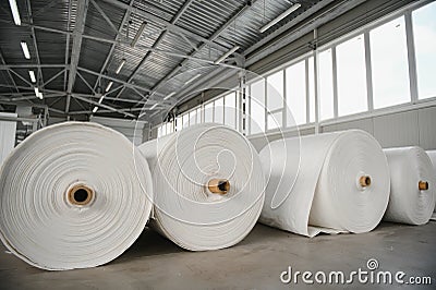 Raw materials warehouse. Many large coils of finished propylene hose made of woven thread for making industrial bags. Stock Photo