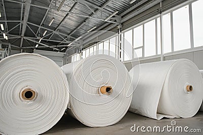 Raw materials warehouse. Many large coils of finished propylene hose made of woven thread for making industrial bags. Stock Photo