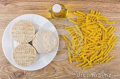 Raw meat cutlets in plate, oil and heap of pasta Stock Photo