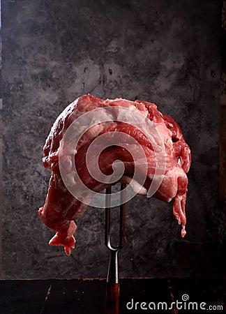 Raw meat stuck on a big fork on a black background Stock Photo