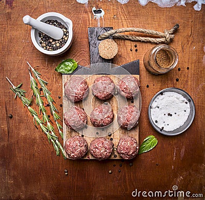 Raw meatballs on a cutting board with herbs and spices wooden rustic background top view close up Stock Photo