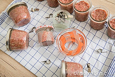 Raw mixed minced meat with pork and beef in screw-cap and preserving mason glass jars on towel for self-made pressure canning in Stock Photo