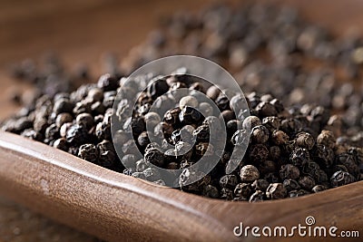 Raw, natural, unprocessed black pepper peppercorns on wooden plate Stock Photo