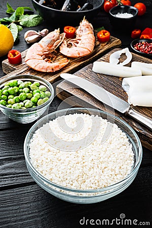 Raw paella ingredients over black wooden table Stock Photo