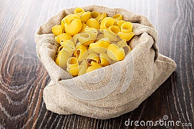 Raw pasta lumache in burlap bag on table Stock Photo