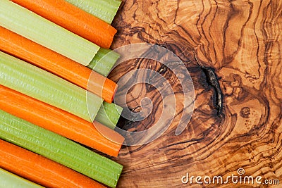 Raw peeled and cut Organic Celery Stalks and Orange Carrots arranged on olive wood. Apiaceae or Umbelliferae family. Delic Stock Photo