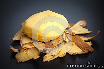 Raw peeled potatoes and potato peelings Stock Photo