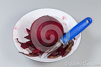 Raw peeled red beetroot and peeler among peelings in bowl Stock Photo