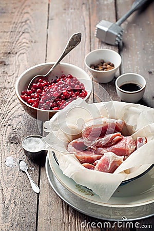 Raw pork in a bowl, cranberries, seasonings and meat hammer Stock Photo