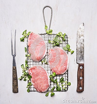 Raw pork steak on the grill with spinach and vintage knife and fork wooden rustic background top view Stock Photo