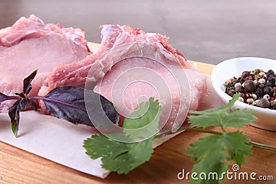 Raw pork steak with spices Leaves of coriander on wooden cutting board. Ready for cooking. Stock Photo