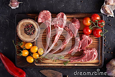 Raw rib of a calf on a cutting board with multi-colored peppercorns, red chili peppers, garlic, yellow and red tomatoes Stock Photo