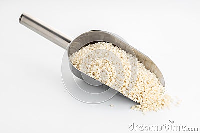Raw rice on metallic scoop isolated on White table Stock Photo