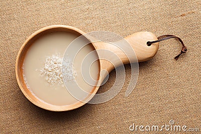 Raw rice and rice water are in wooden dishes. Stock Photo