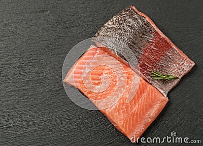 Raw salmon fillet on a dark slate background. Trout fillet with rosemary. Wild atlantic fish Stock Photo