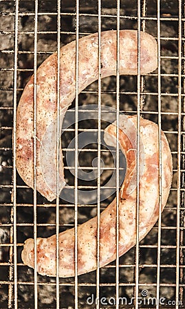 Raw sausages in the grate ready in the grill Stock Photo