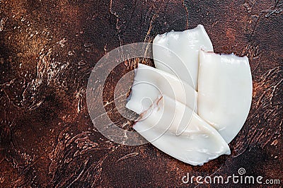 Raw Squid or Calamari tubes on a kitchen table. Dark background. Top view. Copy space Stock Photo