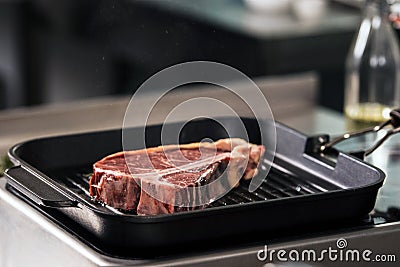 Raw steak lay at griddle pan. Closeup uncooked beef lay at pan. Stock Photo