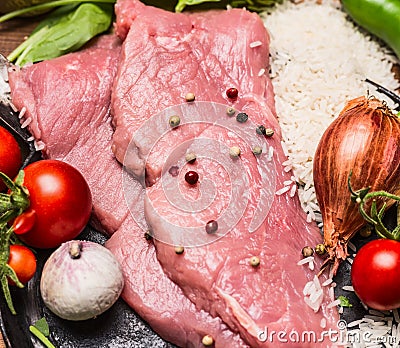 Raw steak turkey tomatoes garlic onion rice in a frying pan top view close up Stock Photo