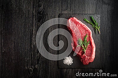 raw strip loin steak on black wooden background Stock Photo