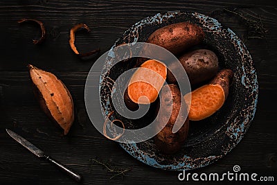 Raw sweet potato on the wooden black table top view Stock Photo