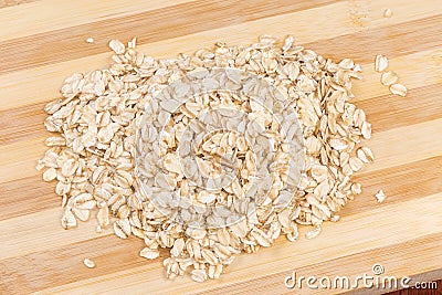 Raw thick-rolled oats on wooden cutting board close-up Stock Photo