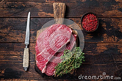 Raw top sirloin cap steak or Picanha steak on wooden board with thyme. Dark wooden background. Top view Stock Photo