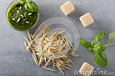 Raw trofie pasta and a glass bowl with pesto souace Stock Photo