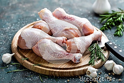 Raw uncooked chicken legs, drumsticks on wooden board, meat with ingredients Stock Photo