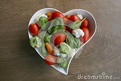 Heart shaped plate with assorted fresh vegetables, top view. Stock Photo