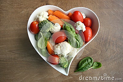 Heart shaped plate with assorted fresh vegetables, top view. Stock Photo