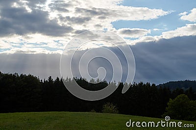 A ray of light breaks through the dramatic sky at sunset and hit an oak tree solitary Stock Photo