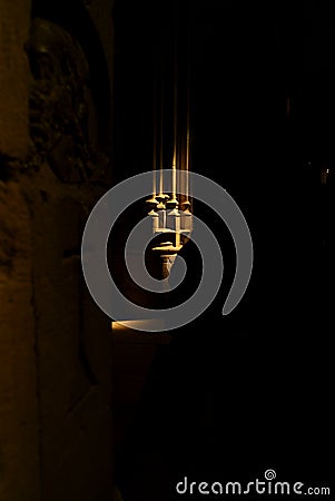 Ray of light in the darkness of a church that illuminates a stone cross Stock Photo