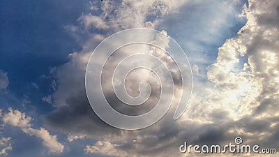 rays from behind the beautiful white clouds form in the blue sky Stock Photo