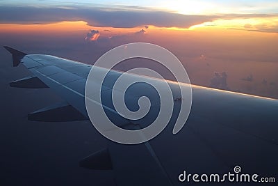 Rays of light in twilight sunset purple orange sky view from window airplane wings Stock Photo