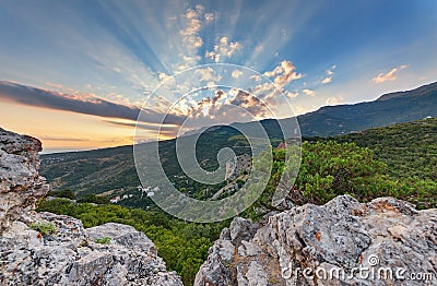 Rays of the sun passing through a cloud above the mountain. The hilly landscape of the valley Stock Photo