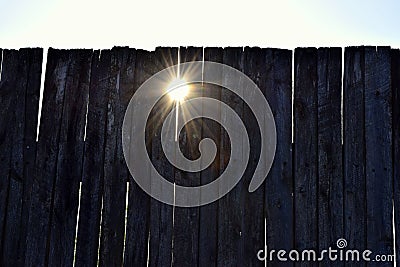 Rays of the sun through the cracks of the fence Stock Photo